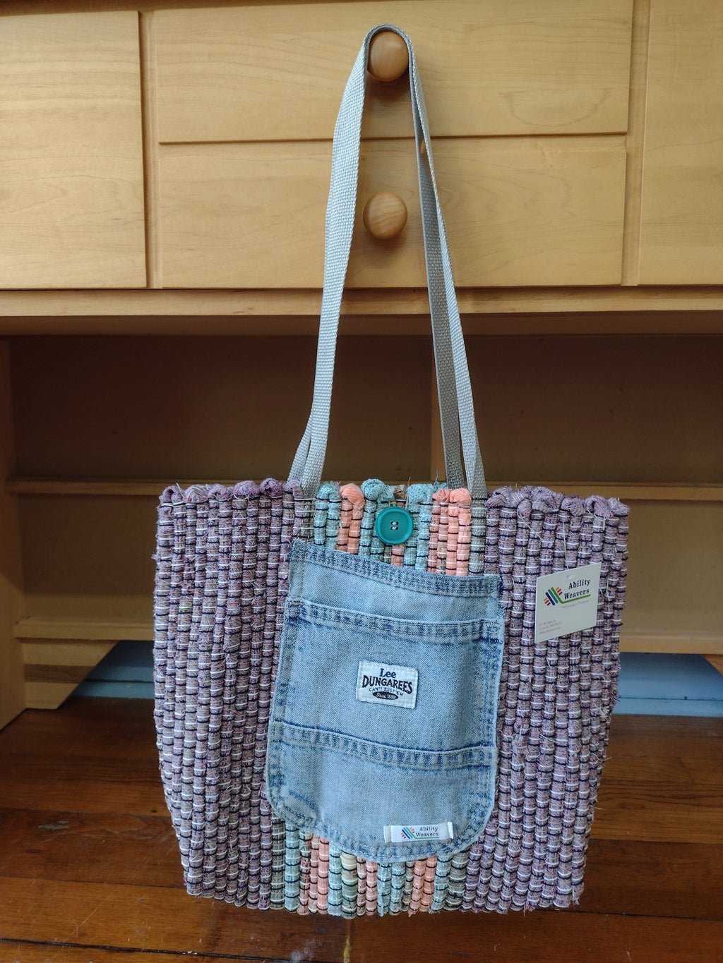 Lavender hand-woven tote bag with a light blue denim front pocket and silver shoulder straps