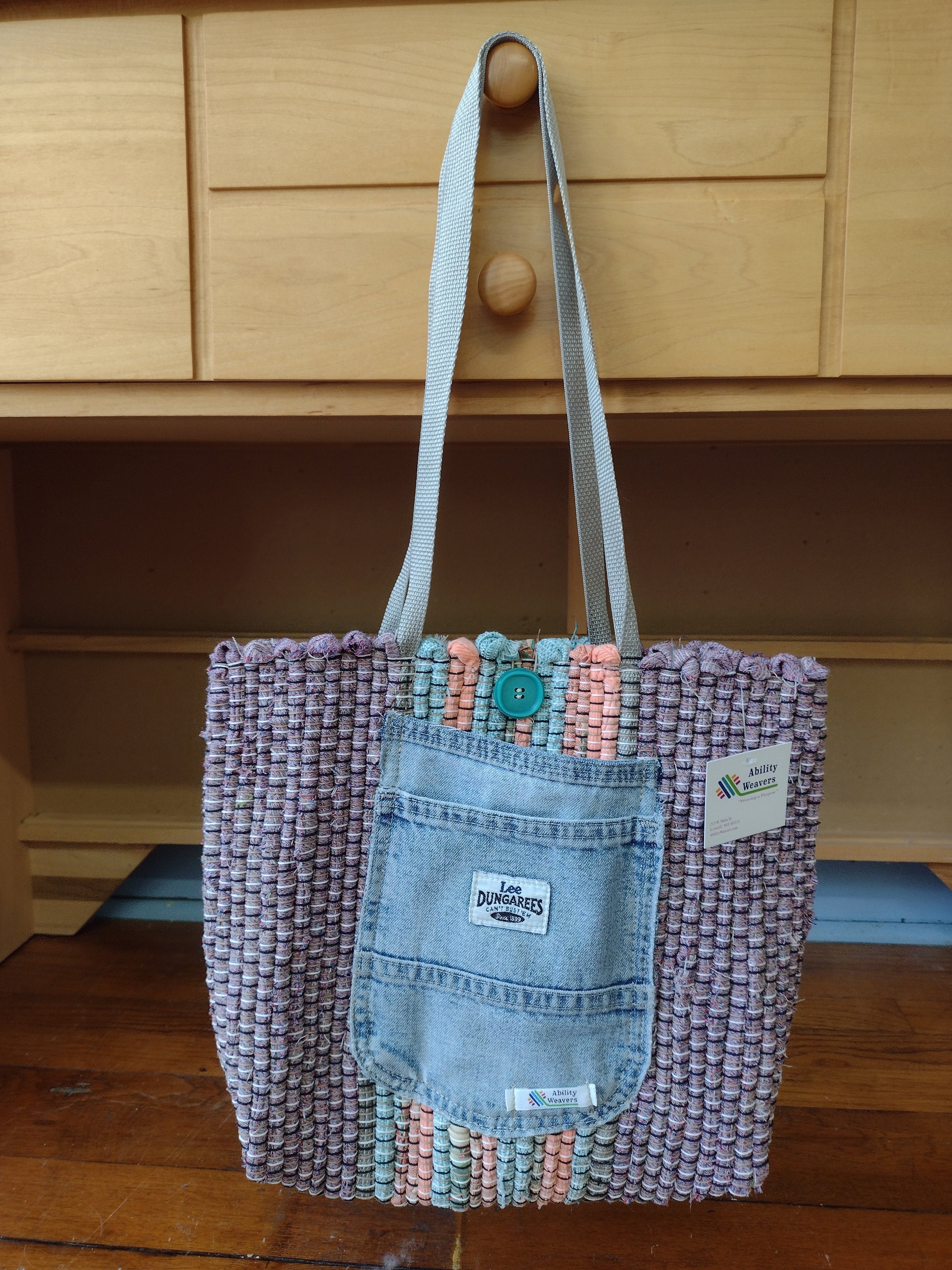 Lavender hand-woven tote bag with a light blue denim front pocket and silver shoulder straps